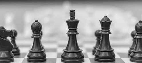 Een zwarte schaakkoning en -koningin met omringende stukken op een bord, die symbool staan voor macht, controle en geavanceerd strategisch spel.