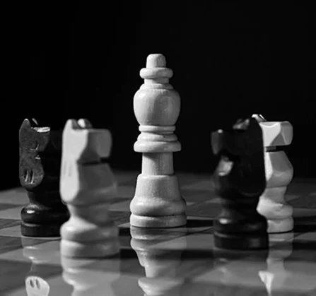 Een wit schaakkoning, omringd door zwarte en witte paarden, die symbool staan voor strategische positionering en controle op het schaakbord.