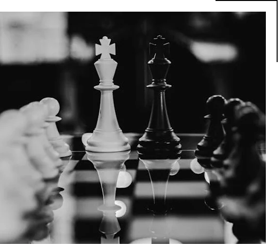 Witte en zwarte koningsstukken die elkaar op een schaakbord tegenover elkaar staan, als symbool voor competitie, rivaliteit en strategische confrontatie.