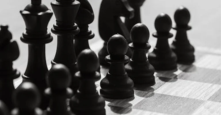 Een rij zwarte schaakstukken opgesteld op een schaakbord, die symbool staan voor formatie, verdedigingsstrategie en competitief spel.